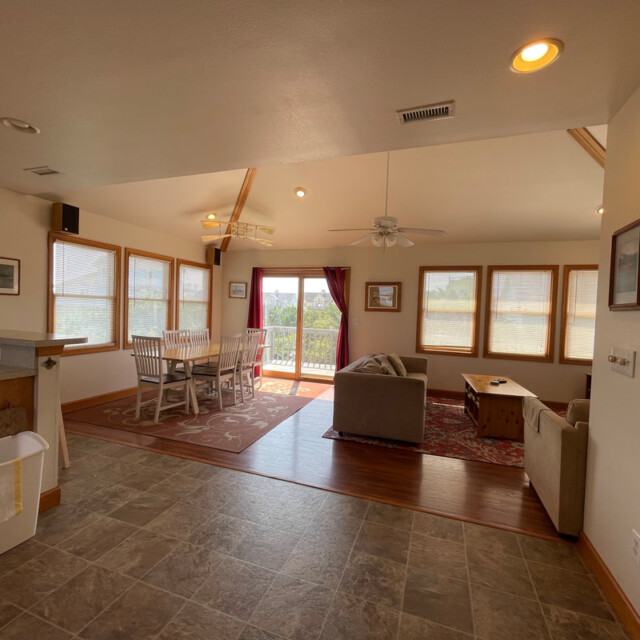 Open living and dining area with tile flooring, couches, dining table, large windows, and a glass door to a balcony.