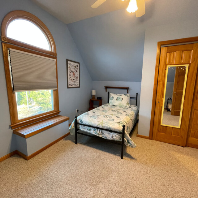 Small bedroom with a single bed, wooden closet doors with mirrors, a window, and light blue walls.