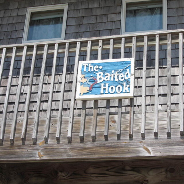 A wooden balcony with a sign that reads “The Baited Hook” featuring a fish and water graphic.
